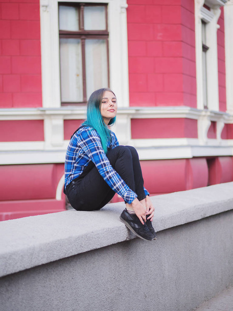 Hipster girl with blue dyed hair. Woman with piercing in nose, ears tunnels and unusual hairstyle having fun, posing in European city. Carefree concept. - Foto, Imagem