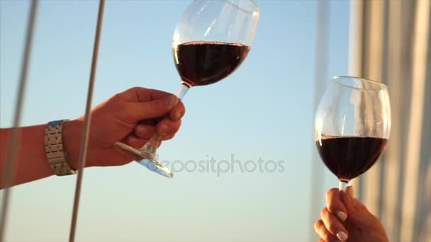Звон бокалов с красным вином в руках мужчины и женщины, крупным планом
. - Кадры, видео