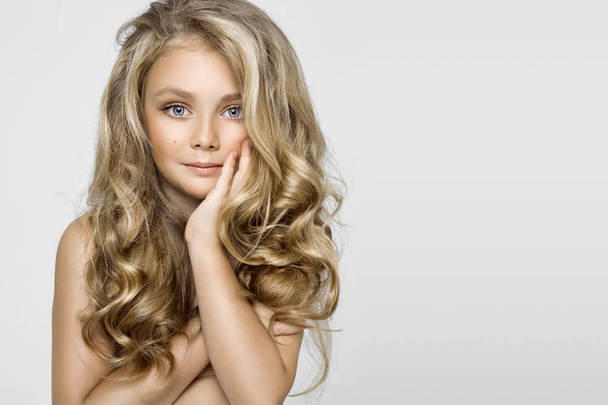schönes junges blondes Model, nettes Mädchen mit langen schönen Haaren auf weißem Hintergrund. elegantes kleines Mädchen - Foto, Bild