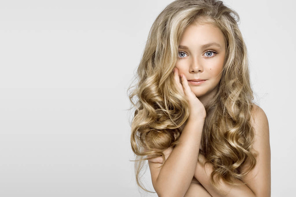Молодая блондинка-модель, симпатичная девушка с длинными красивыми волосами на белом фоне. Элегантная маленькая девочка
 - Фото, изображение