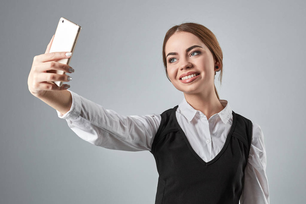 Portrait of young caucasian business woman in suit doing selfie on the phone. - Фото, изображение