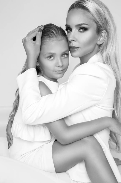 Beautiful blonde female model, mother with blonde daughter hug. They have beautiful tanned body. - Photo, Image