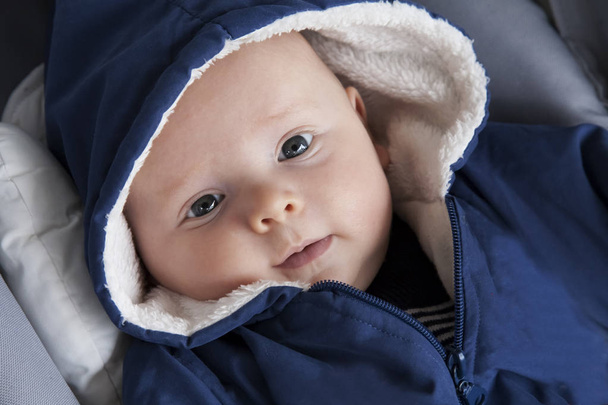 Portrait en gros plan d'un mignon tout-petit en tenue chaude lors d'une promenade. Portrait d'un bébé dans une capuche. - Photo, image