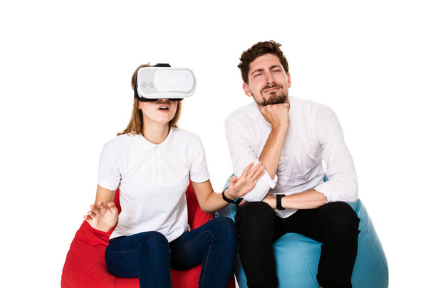 Izgatott fiatal pár tapasztalják beanbags elszigetelt fehér background ülő virtuális valóság - Fotó, kép