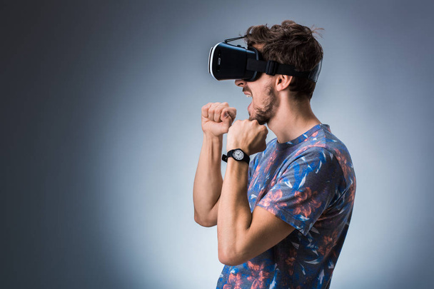 Side view of a young guy using a VR headset. Emotions - Fotoğraf, Görsel