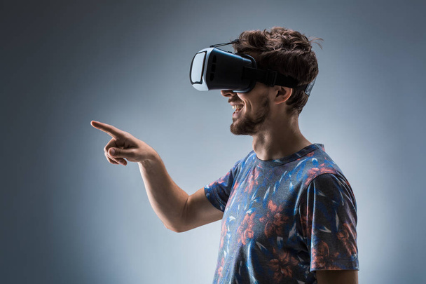 Πλαϊνή όψη, ένας νεαρός άντρας, χρησιμοποιώντας μια συσκευή VR. Συναισθήματα - Φωτογραφία, εικόνα