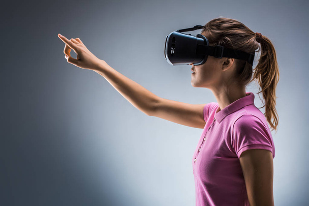 Mladá žena nosí soupravu pro virtuální realitu ve studiu. Emoce. Boční pohled - Fotografie, Obrázek