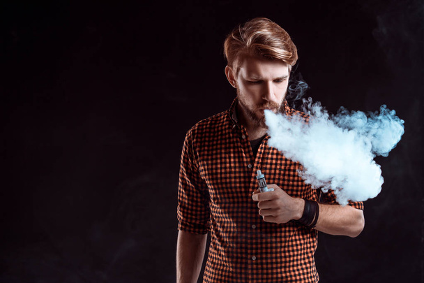 νεαρός άνδρας που καπνίζει ηλεκτρονικό τσιγάρο - Φωτογραφία, εικόνα