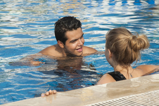 Ζευγάρι ερωτευμένο να κολυμπάει στην πισίνα. Δύο όμορφοι νεαροί έφηβοι διασκεδάζουν στην πισίνα. Concept ταξίδια, διακοπές και αγάπη. - Φωτογραφία, εικόνα