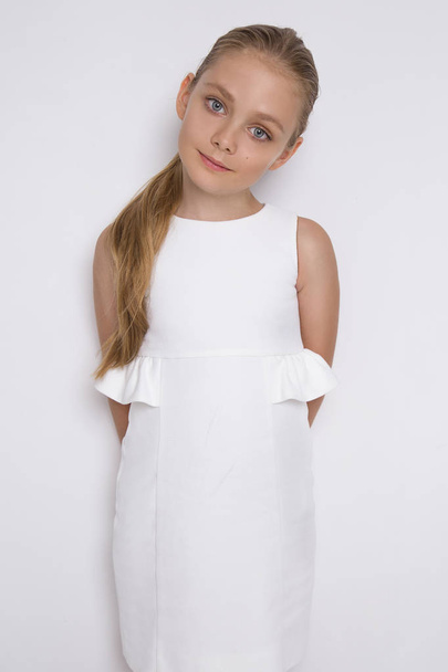 schöne blonde junge Modell, nettes Mädchen, in weißem Kleid auf weißem Hintergrund. elegantes kleines Mädchen - Foto, Bild