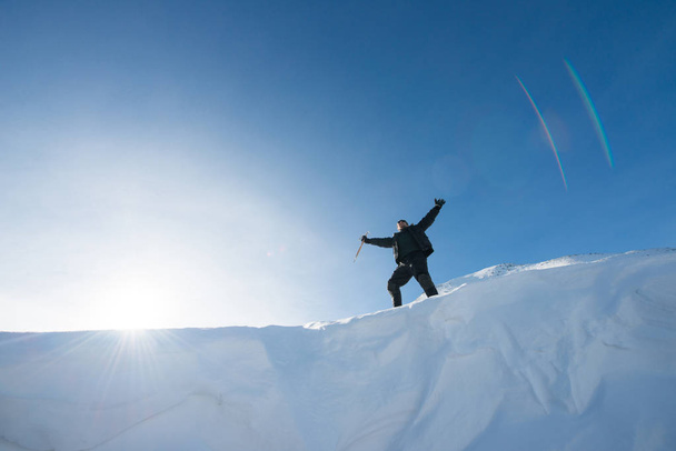 Happy climber with an ice ax in the snowy mountains - Фото, изображение