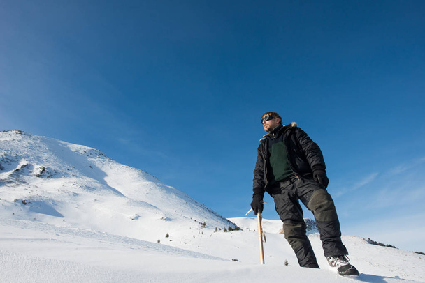 climber with an ice ax in the snowy mountains - Fotó, kép