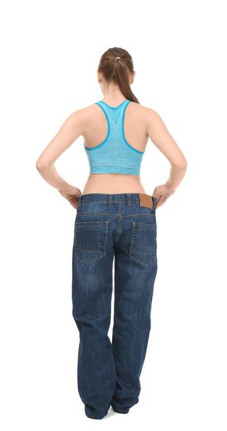 Young woman in oversized jeans on white background. Diet concept - Valokuva, kuva
