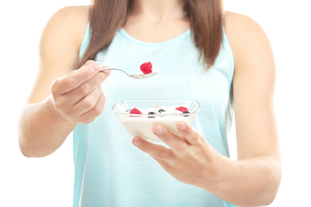 Young woman eating yogurt on white background - Фото, изображение
