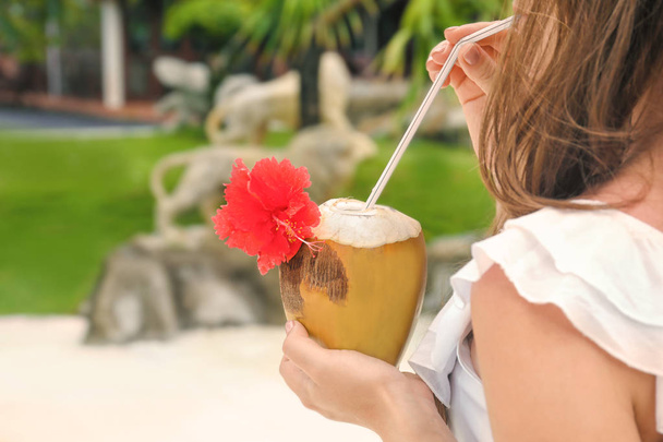 Young woman with fresh coconut cocktail at resort - Фото, зображення