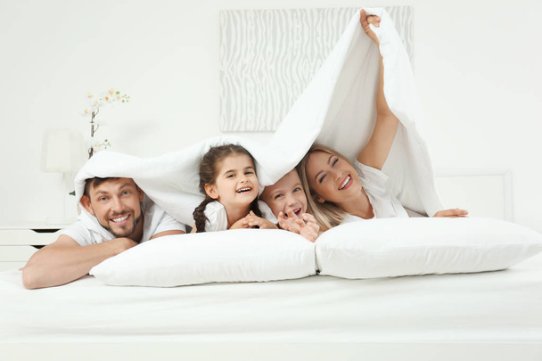 Family lying on bed in hotel room - Фото, изображение
