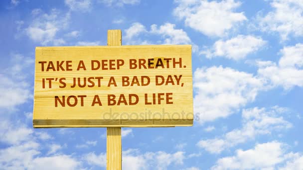 Neem een diepe adem. Het is gewoon een slechte dag, niet een slecht leven. Woorden op een houten bord tegen tijd vervallen wolken in de blauwe hemel. - Video
