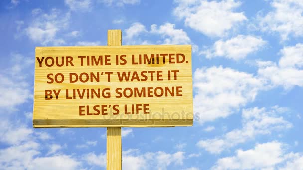 Your time is limited. So don't waste it by living someone else's life. Words on a wooden sign against time lapse clouds in the blue sky. - Footage, Video