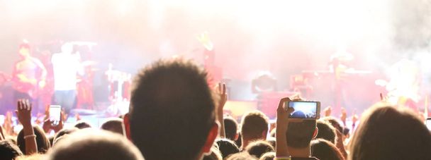 ファンは、ライブ コンサートの中に近代的なスマート フォンで写真を撮る  - 写真・画像