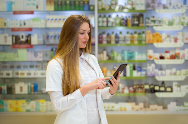 Gelukkig jonge vrouw apotheker over drogisterij achtergrond, houden  - Foto, afbeelding