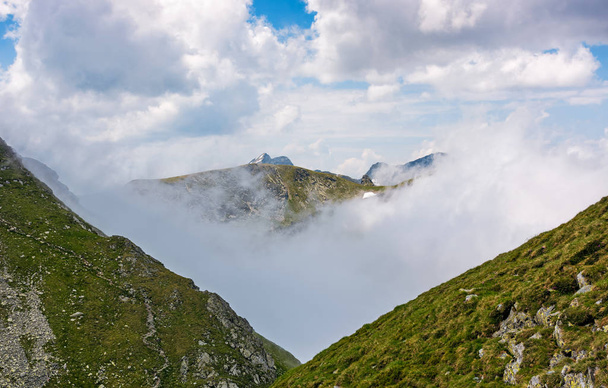 high mountain peak in clouds among the hills - Photo, image