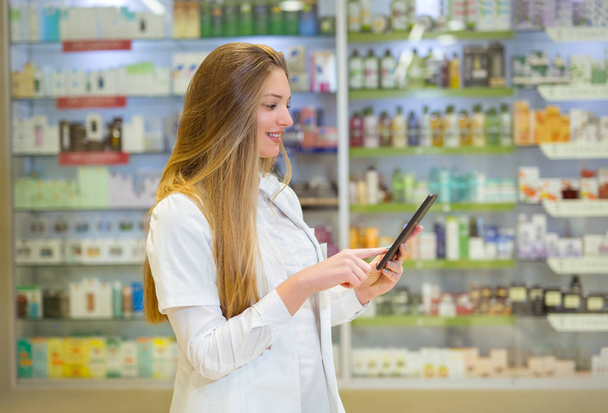 Happy young woman pharmacist over drugstore background, holding  - Photo, image