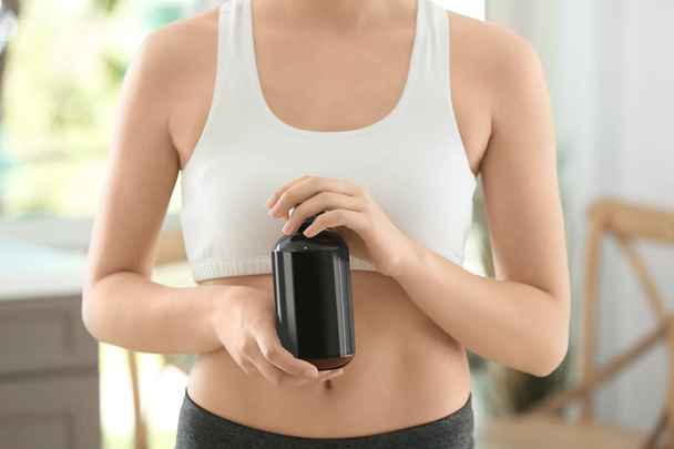 Young woman with bottle of sport supplement at home. Diet concept - Photo, Image
