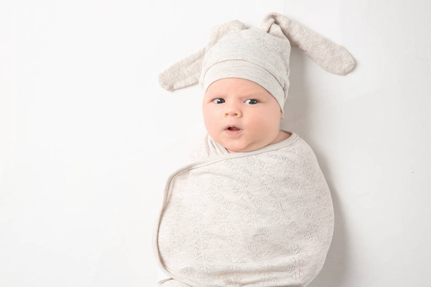 Cute newborn baby in cocoon and funny hat on white background - 写真・画像