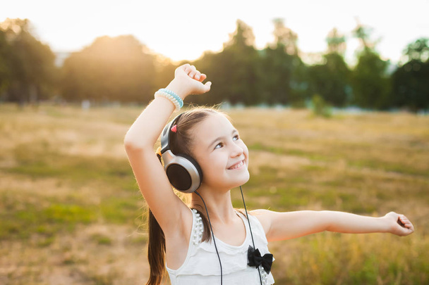 joyful girl listening music and dancing in the field - Photo, Image