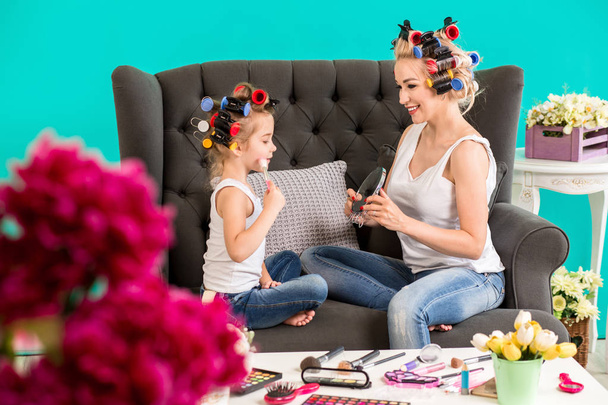 Portrait of cute little girl and her mom doing each other makeup - Photo, Image