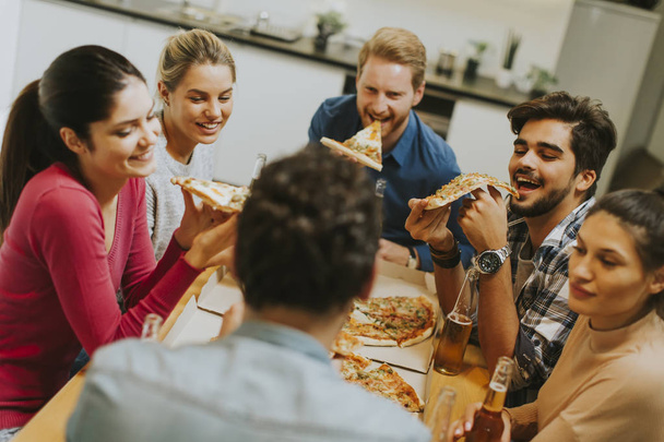 Молоді люди їдять піцу і п'ють сидр
 - Фото, зображення
