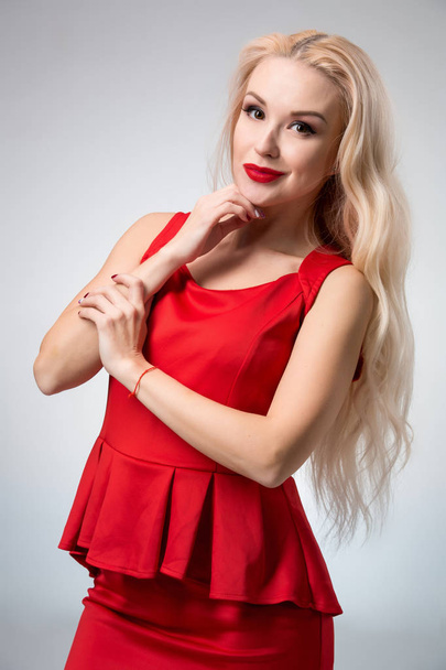 glamouröse junge Frau in rotem Kleid auf grauem Hintergrund - Foto, Bild