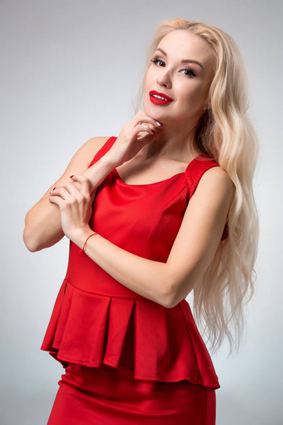 Okouzlující mladá žena v červených šatech na šedém pozadí - Fotografie, Obrázek