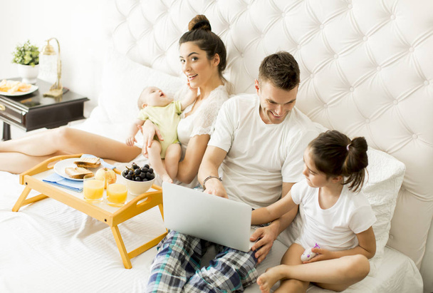 Nuori perhe kannettavan tietokoneen kanssa
 - Valokuva, kuva