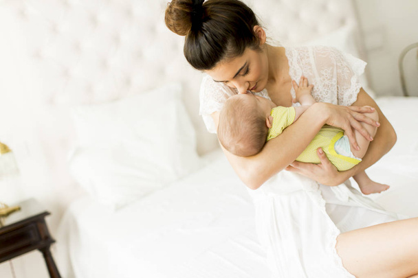 Young mother and cute baby girl on the bed - Foto, Bild