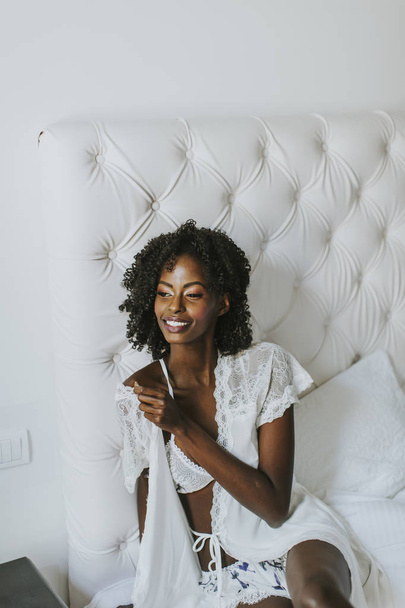 afroamericano donna in bianco in posa sul letto
 - Foto, immagini