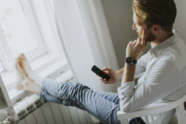 Komea punatukkainen mies kirjoittaa viestin puhelimeen
 - Valokuva, kuva
