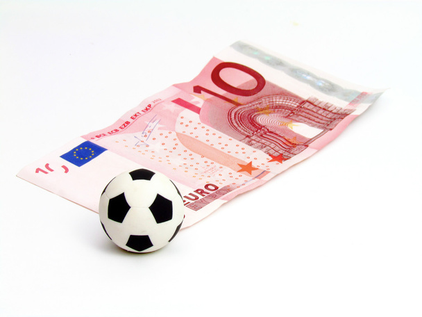 Pelota de fútbol sobre la esquina de un billete de 10 euros sobre un fondo blanco
 - Foto, Imagen