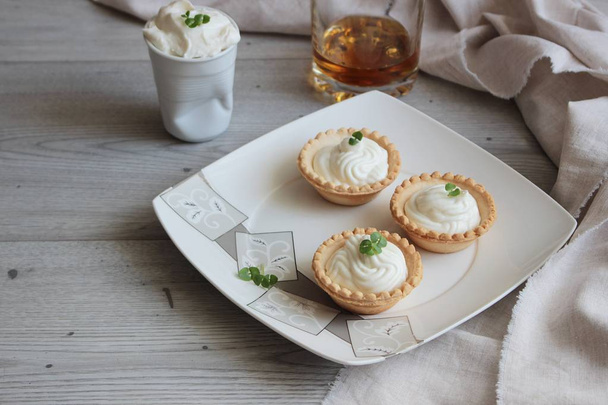 Antipasti tartlets with gentle cheese mousse served with herbs on wooden grey texture background with textile. - 写真・画像