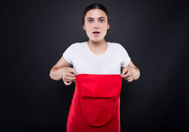 Amazed female employee wearing red apron - Fotoğraf, Görsel