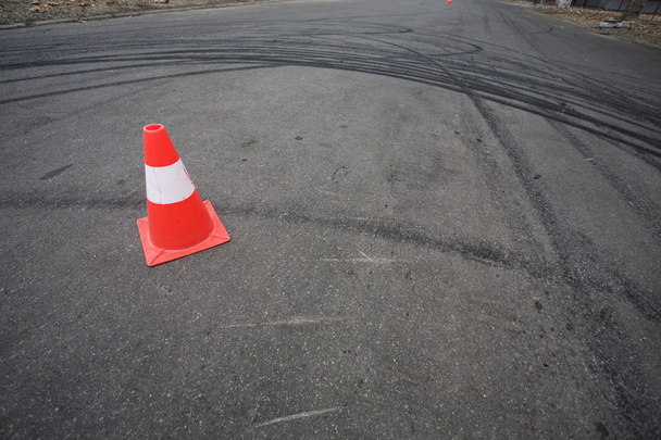 Cone de tráfego laranja e marcas de derrapagem
 - Foto, Imagem