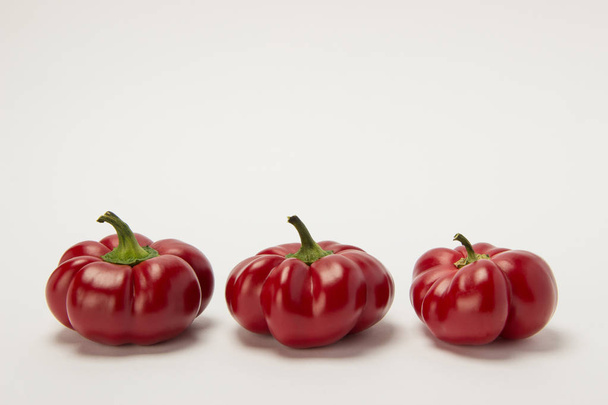 Three ripe red sweet peppers on a white background - Valokuva, kuva