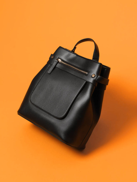 Beautiful luxury leather female black bag on an orange background - 写真・画像
