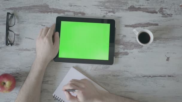 mãos masculinas fazer anotações em um caderno, em seguida é um tablet com uma tela verde
 - Filmagem, Vídeo