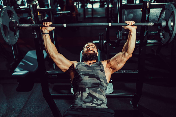 handsome young man doing bench press workout in gym - Foto, Bild