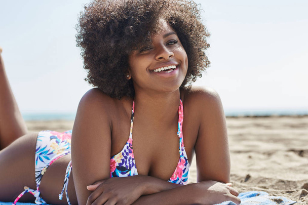 Young beautiful afro american woman lying on beach - 写真・画像