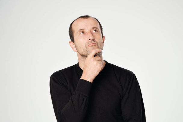 Кавказький чоловік у чорні сорочки, дивлячись з скептично емоцій на обличчі. - Фото, зображення
