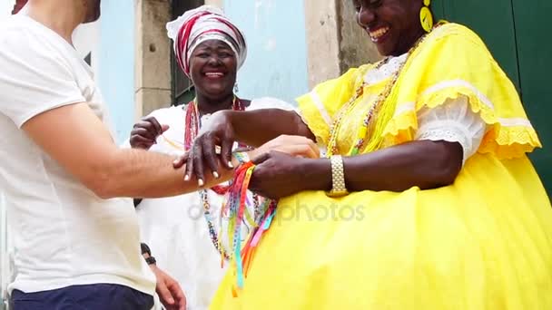 Baianas tyytyväinen turisti antaa joitakin "Brasilian toivomusnauhoja" Salvadorissa, Brasiliassa nauhat pidetään onnea hurmaa
 - Materiaali, video
