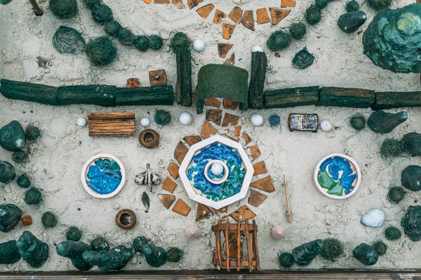 Песочная терапия. Вид сверху игрушечных миниатюрных деревьев и небольших элементов ландшафта в песочнице
 - Фото, изображение