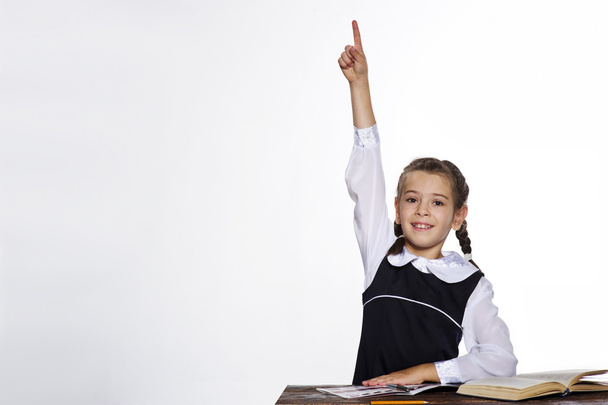 Студійний портрет чарівної маленької школярки піднімає руку
 - Фото, зображення